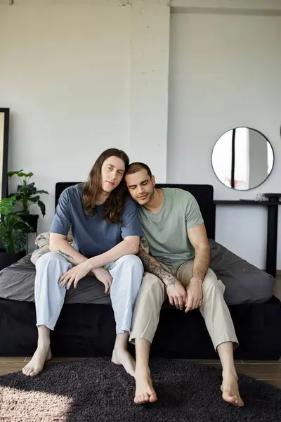 A young gay couple relaxes and enjoys each others company in a bedroom setting. — Stock Photo