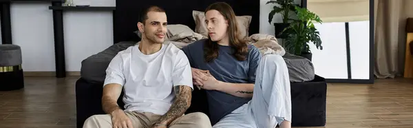 A young gay couple relaxes together in a modern bedroom, sharing a quiet moment of intimacy. — Stock Photo