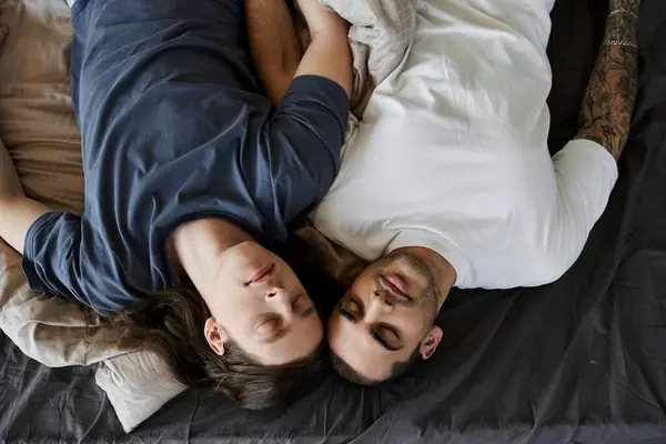 Two young men are lying in bed together, asleep and holding each other. — Stock Photo