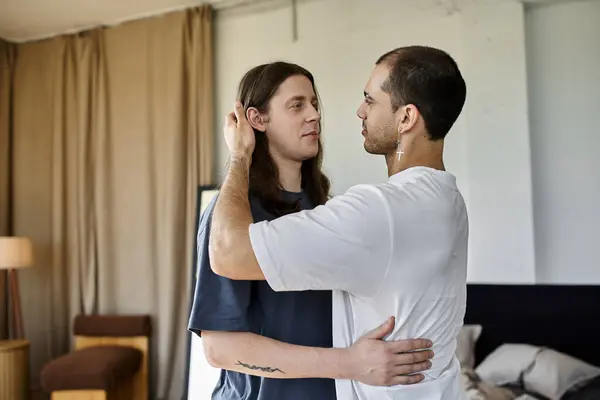 A young gay couple stands close together in a bedroom, sharing a tender moment of intimacy. — Stock Photo