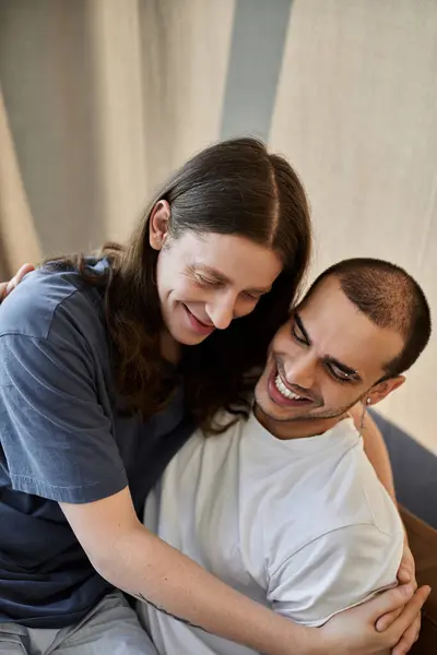 A young gay couple shares a tender moment, embracing in a comfortable modern home setting. — Stock Photo