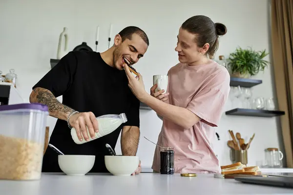 A young gay couple enjoys a lighthearted breakfast in their modern kitchen, full of laughter and playful affection. — Stock Photo