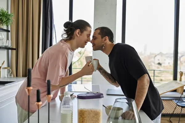 A young gay couple shares a tender moment while enjoying coffee in their modern home. — Stock Photo