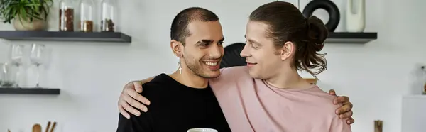A young gay couple shares a tender moment in their modern kitchen, their smiles reflecting their love and happiness. — Stock Photo