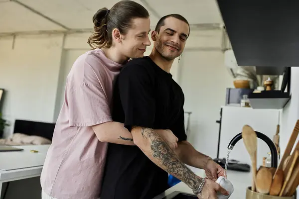 Una giovane coppia gay mostra affetto mentre fa i piatti nella loro cucina moderna. — Foto stock
