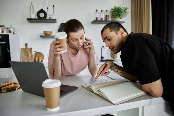 A young gay couple enjoys a morning coffee and plans their day in their modern kitchen. — Stock Photo