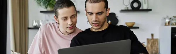 Two young men, a gay couple, are looking at a laptop screen together in their modern home. — Stock Photo