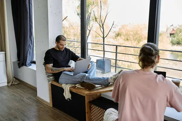 A young gay couple spends time together in a modern home. One partner works on a laptop while the other sits nearby. — Stock Photo