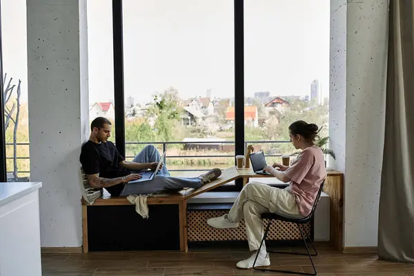 Um jovem casal gay relaxa em sua casa moderna, desfrutando de uma tarde pacífica com seus laptops. — Fotografia de Stock