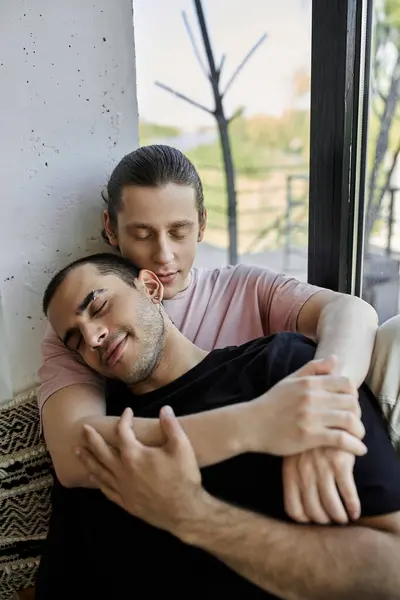 Two young men cuddle together, eyes closed, in a modern home, enjoying a peaceful moment of intimacy. — Stock Photo