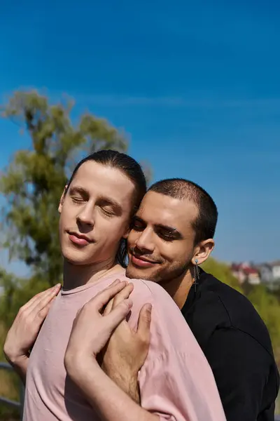 A young gay couple shares a tender moment of affection outdoors on a sunny day. — Stock Photo