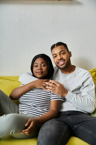 Ein liebevolles afroamerikanisches Paar entspannt sich zu Hause auf einer gelben Couch. — Stockfoto