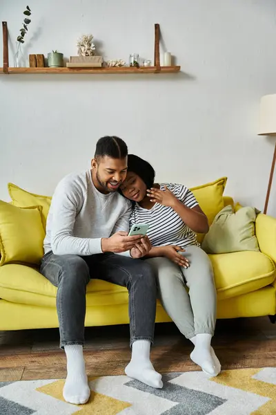 Happy African American couple laughs on yellow couch at home. — Stock Photo