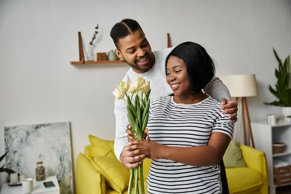 A man gives his wife a bouquet of flowers at home. — Stock Photo