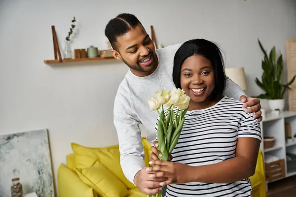 A happy African American couple share a bouquet of flowers in their home. — Stock Photo