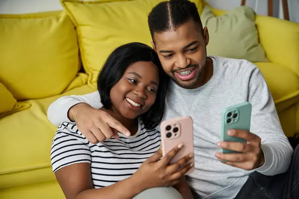 A loving African American couple spends a relaxing evening at home, engrossed in their smartphones. — Stock Photo