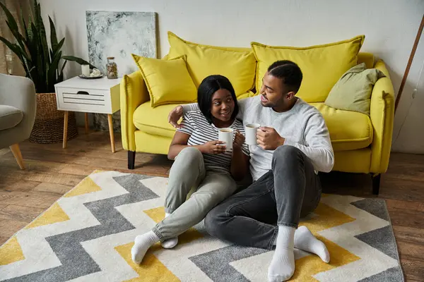 A loving African American couple enjoys a relaxing moment together at home, sharing a cup of coffee. — Stock Photo