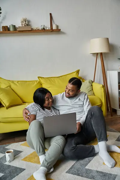 A loving couple relaxes on the floor at home, sharing a laptop and a moment together. — Stock Photo