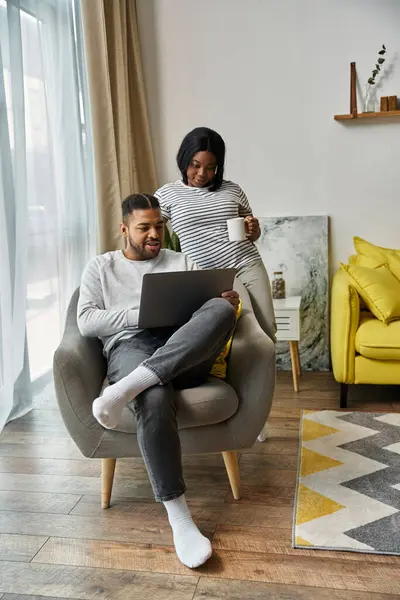 An African American couple at home, man on laptop, woman with coffee. — Stock Photo