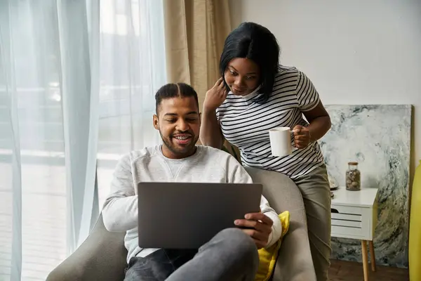 African American couple cozy at home, using laptop and enjoying drink. — Stock Photo