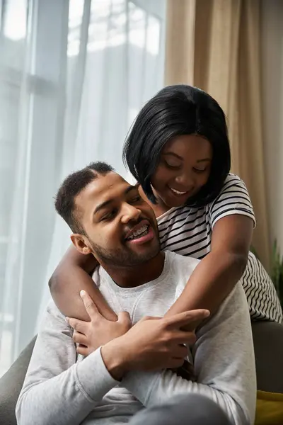 An African American couple embraces each other affectionately in their living room. — Stock Photo