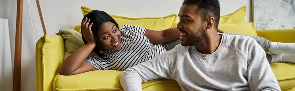 Um casal afro-americano desfruta de um momento acolhedor juntos em um sofá amarelo. — Fotografia de Stock