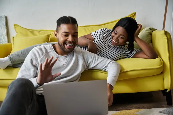 A happy couple, man and woman, relax on a yellow couch at home. — Stock Photo