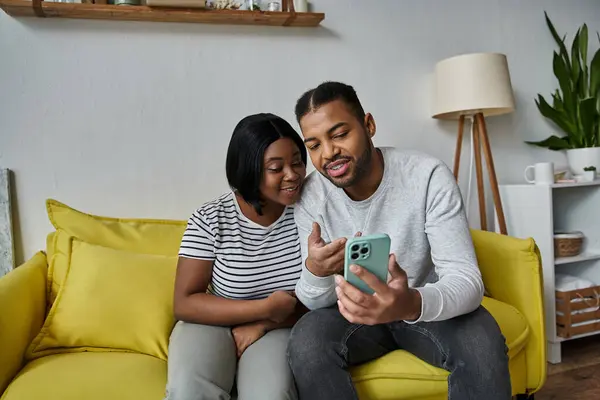 A loving African American couple spends quality time together at home, looking at a phone. — Stock Photo