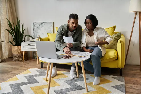 An African American couple review papers and relax on their couch. — Stock Photo
