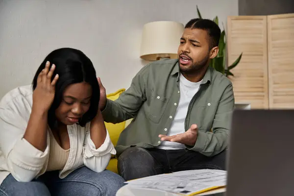 A young African American couple sits together at home, engaged in a deep conversation. — Stock Photo