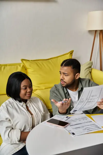 Una coppia afroamericana amorevole siede a un tavolo, rivede documenti e discute di finanze. — Foto stock