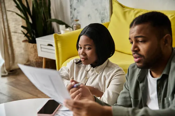 A couple sits together at home, reviewing documents. — Stock Photo