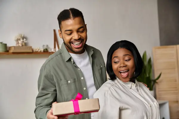 A happy African American couple celebrating at home with a gift. — Stock Photo