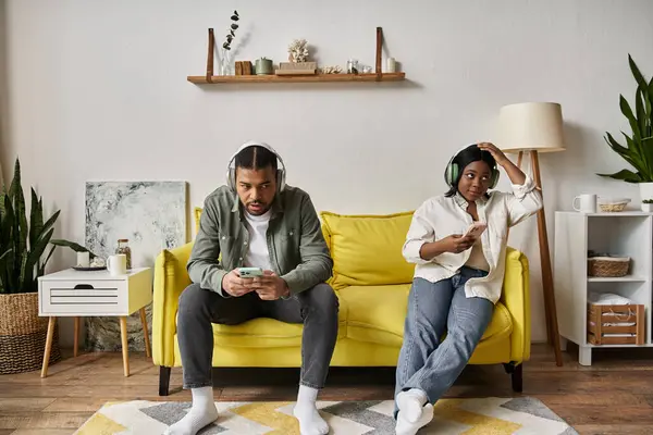 A loving African American couple spends time together on a yellow sofa in their home. — Stock Photo