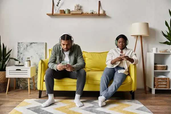 Una pareja afroamericana amante se relaja en un sofá amarillo en su casa. - foto de stock