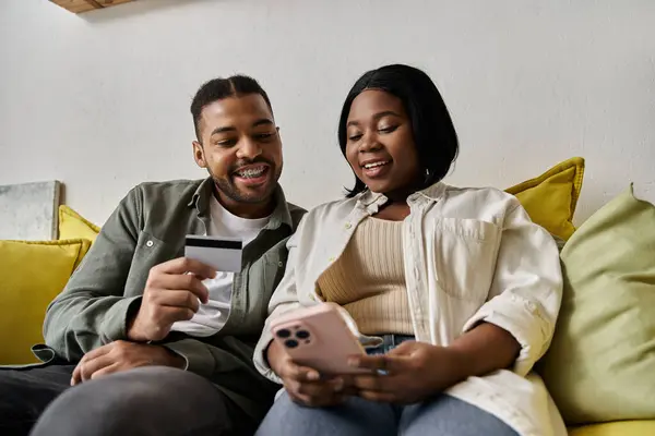 An African American couple smiles while shopping online together at home. — Stock Photo