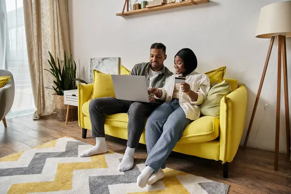 Coppia afroamericana negozi online, si rilassa sul divano giallo. — Foto stock
