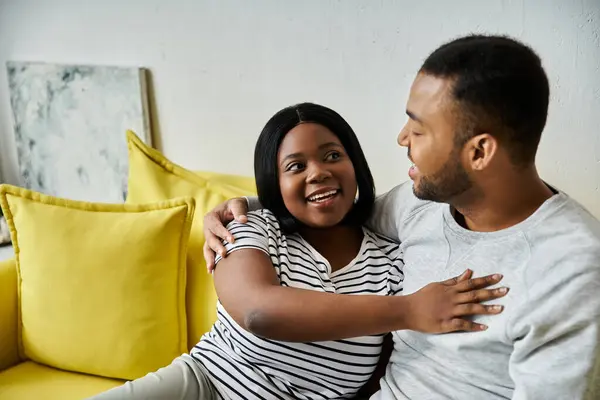 Un couple afro-américain amoureux partage un moment tendre sur un canapé jaune. — Photo de stock