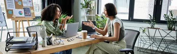 Two women, a lesbian couple, work together on a project in a modern office setting. — Stock Photo