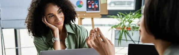 A lesbian couple works together on a laptop in a modern office. — Stock Photo