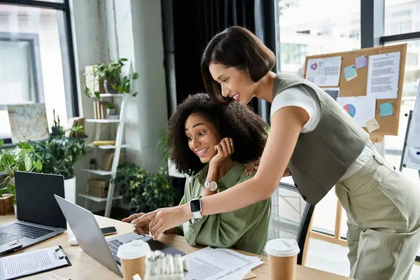 Two women work together on a laptop in a modern office. — Stock Photo