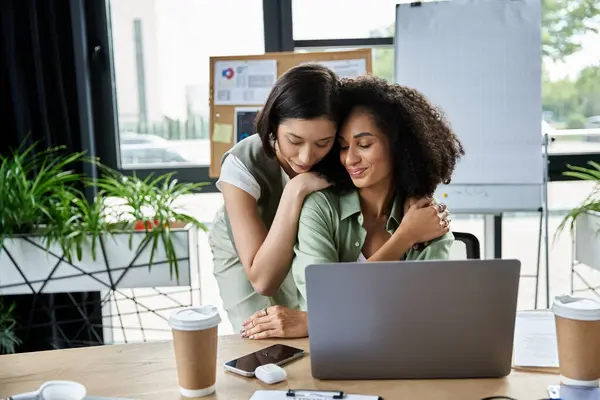 Two women in a loving relationship embrace at work. — Stock Photo