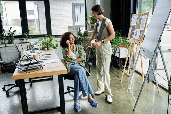 Two women in a loving relationship work together in a bright office space. — Stock Photo