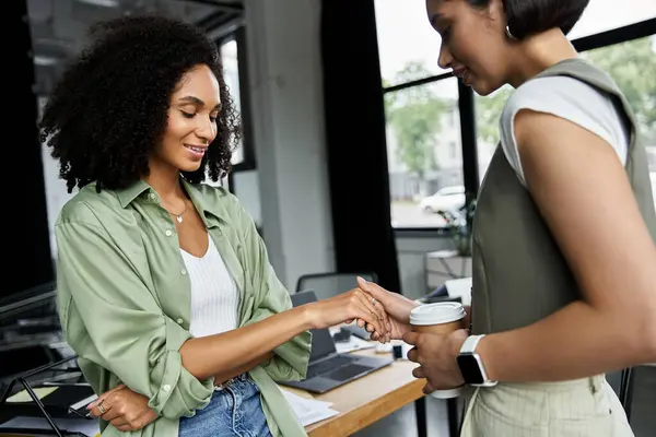 Deux femmes, un couple de lesbiennes, se sourient en travaillant dans un bureau. — Photo de stock