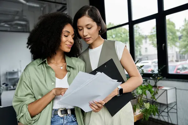 Two women, partners in both love and work, review documents together in an office setting. — Stock Photo