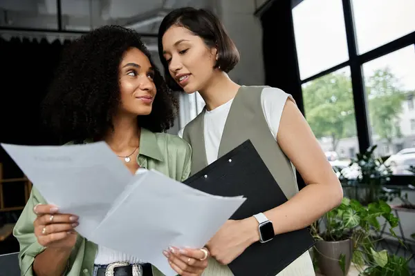 Two women working together in an office, reviewing documents. — Stock Photo