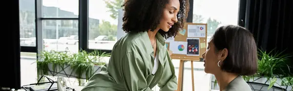 Two women, a lesbian couple, look at each other affectionately while working in an office. — Stock Photo