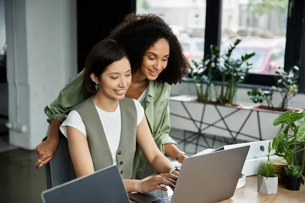 Two women, partners, collaborating on a laptop in a modern office. — Stock Photo