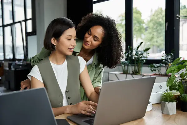 Two women work together on a laptop in a bright office space. — Stock Photo