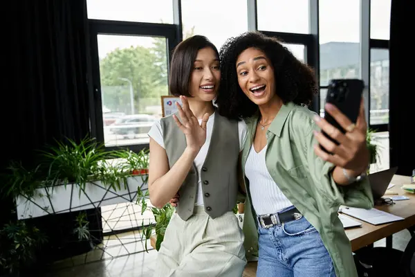 Duas mulheres tiram uma selfie em um ambiente de escritório. — Fotografia de Stock